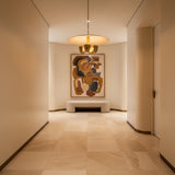 Sonoma 4 light sculptural chandelier shown from the front with a wide cream disc shade, brass-tone bowl lights, and slender downrod.