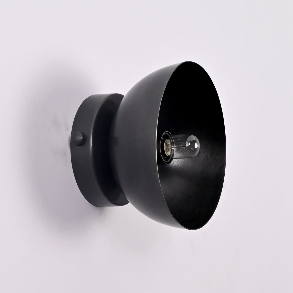 Perspective detail of the Sutton Modern Dome Wall Sconce highlighting the smooth handcrafted dome shade and exposed bulb socket.