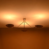 Illuminated three-light brass chandelier casting warm indirect glow, handcrafted ceiling fixture