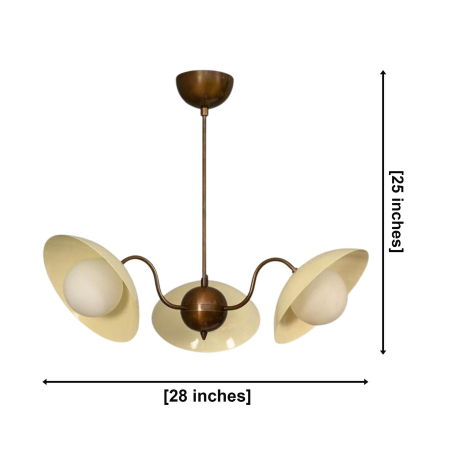 Toledo 3 light cream and aged brass chandelier illuminated in a warm Mid-Century modern living room above a coffee table.