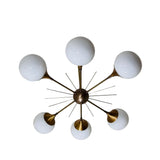 Toledo 6 light sculptural globe chandelier shown from below with six opal glass globes arranged around a brass-tone starburst central hub.