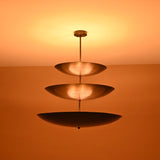 Close-up of illuminated triple bowl chandelier in blackened brass finish, showcasing soft indirect light