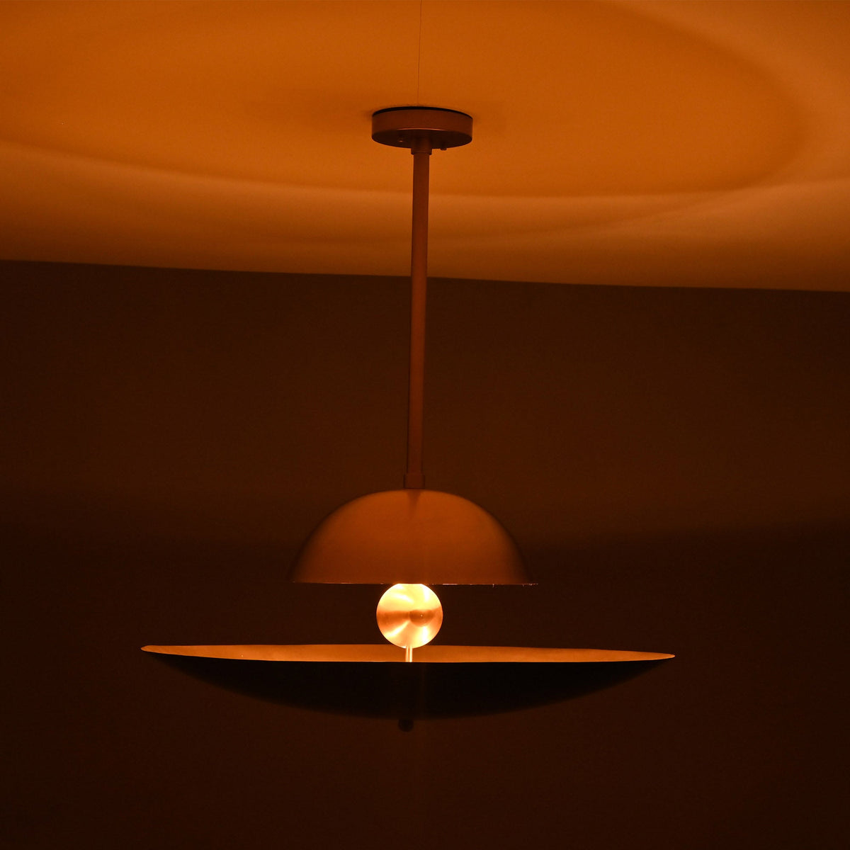 Venice Disc pendant glowing warmly above a dining table, highlighting its layered double-disc shade design.