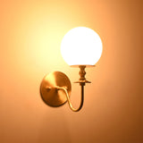Verona Modern Globe Glass Wall Sconce casting a soft warm ambient glow against the wall, highlighting its frosted globe shade.
