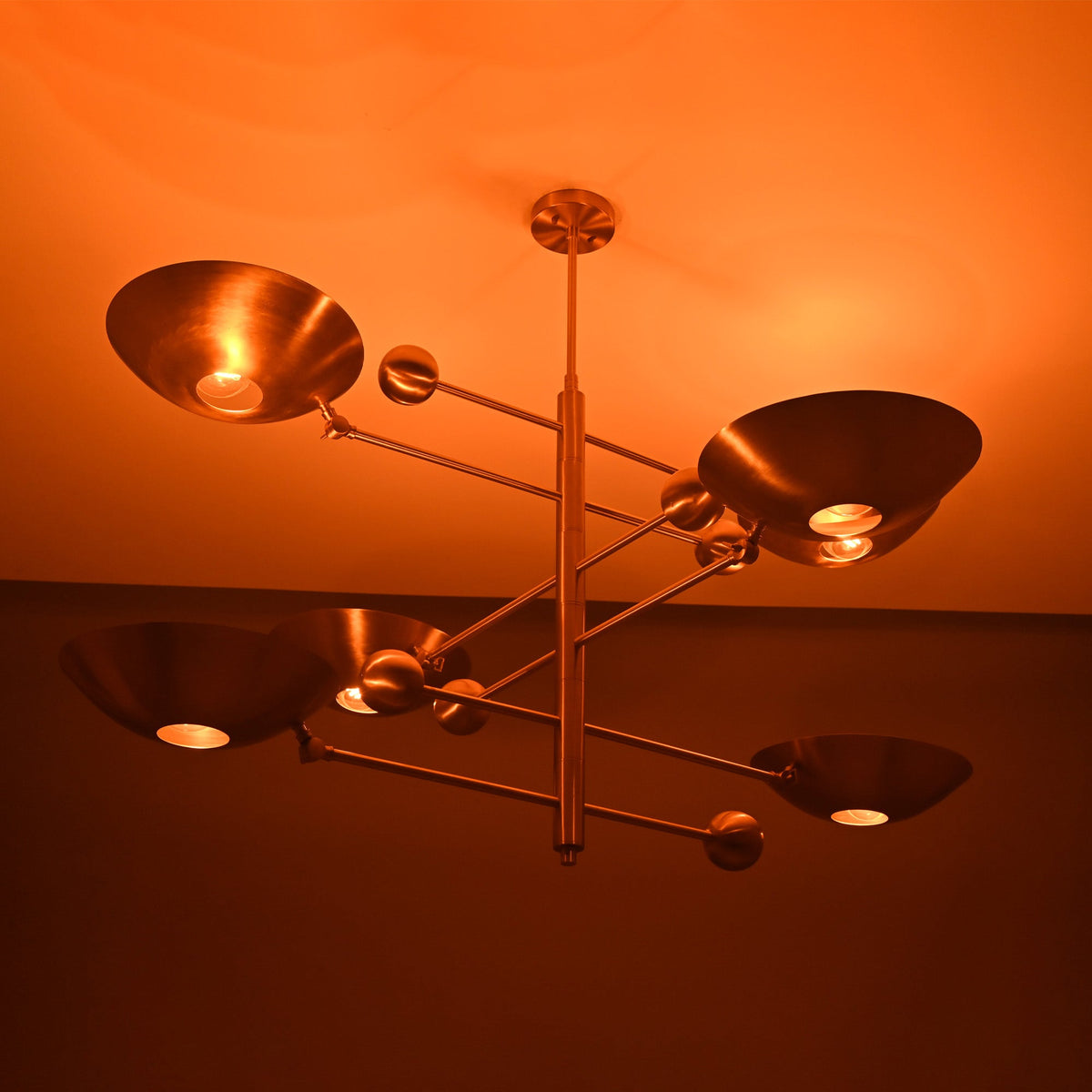 Verona Orbital chandelier shown illuminated from an angled view, highlighting layered bowl shades and warm glow.