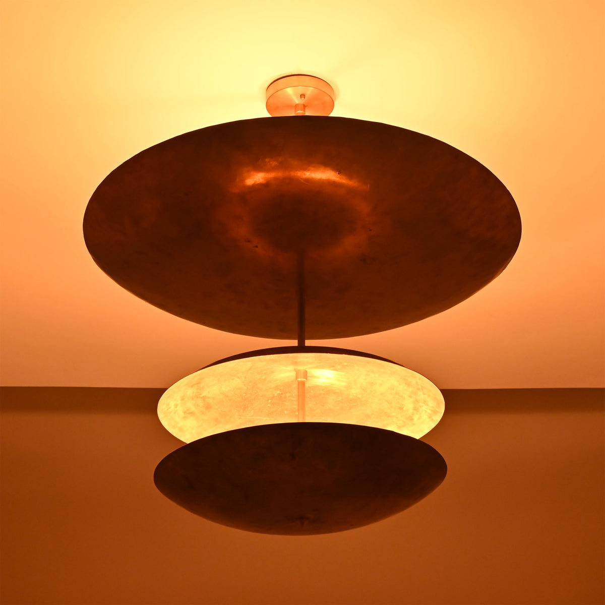 Verona Triple Saucer Chandelier shown from below with sculptural stacked shades and dramatic warm lighting.