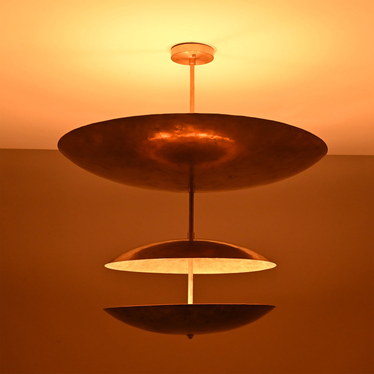 Verona Triple Saucer Chandelier glowing warmly with three layered saucer shades and soft ambient illumination.