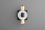 Minimal wall sconce with white round disc on black square plate and two vertical Edison filament bulbs, modern industrial wall lighting.