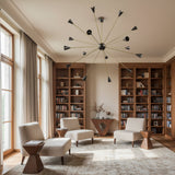 York 16 light Mid-Century Modern starburst chandelier with long antique brass tone arms and contrasting black cone-shaped socket covers.