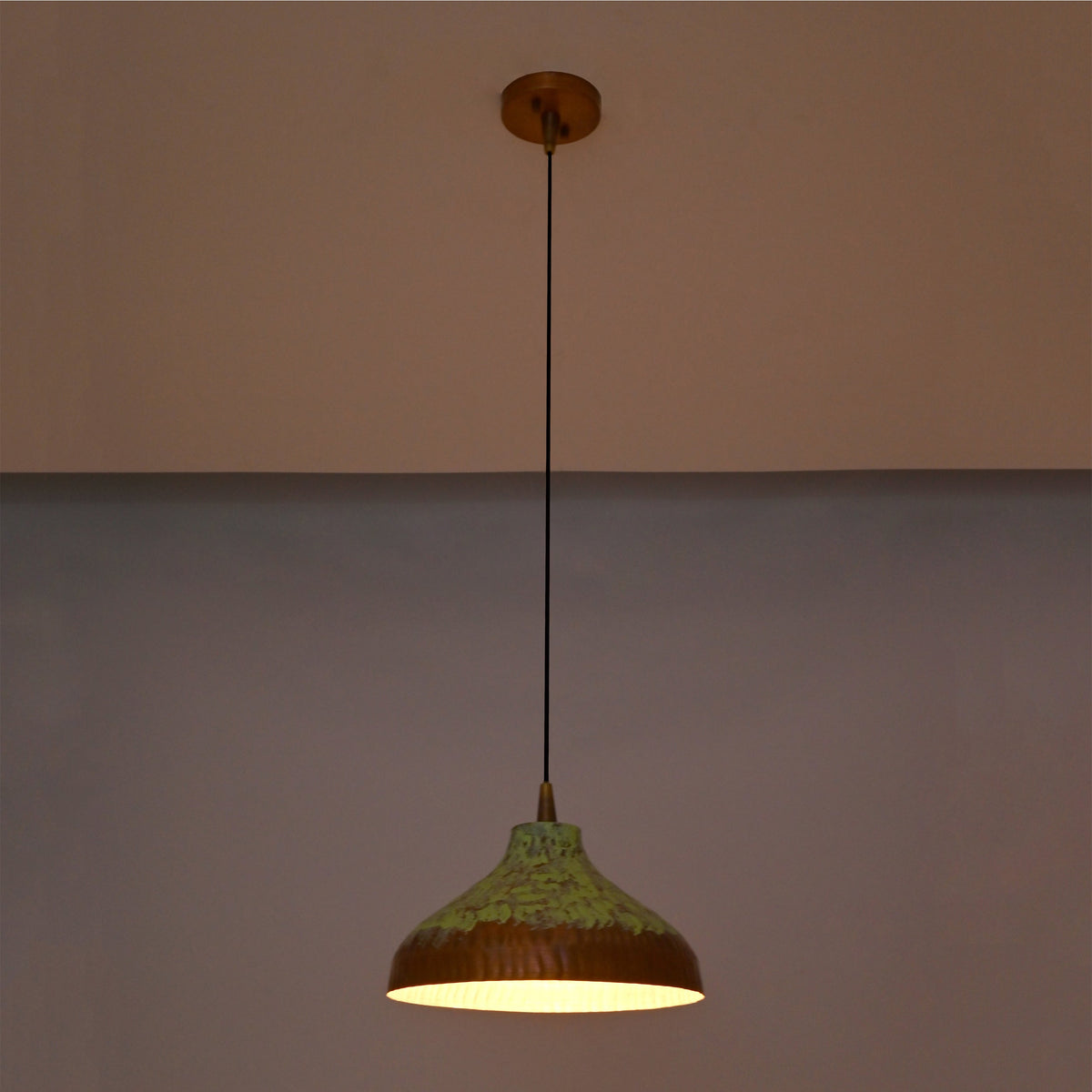 Artistic copper hanging pendant light with green patina finish, black suspension cord, and wide shallow dome shade