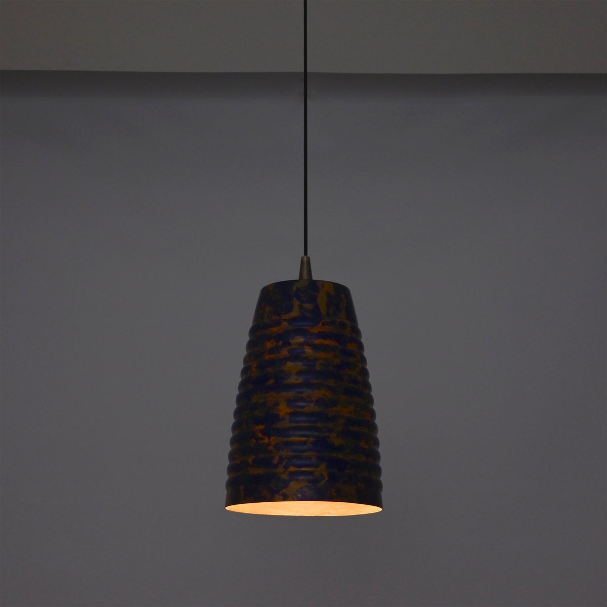 Artistic ribbed pendant light adding warm ambient glow to a stylish interior with wooden furniture and soft décor