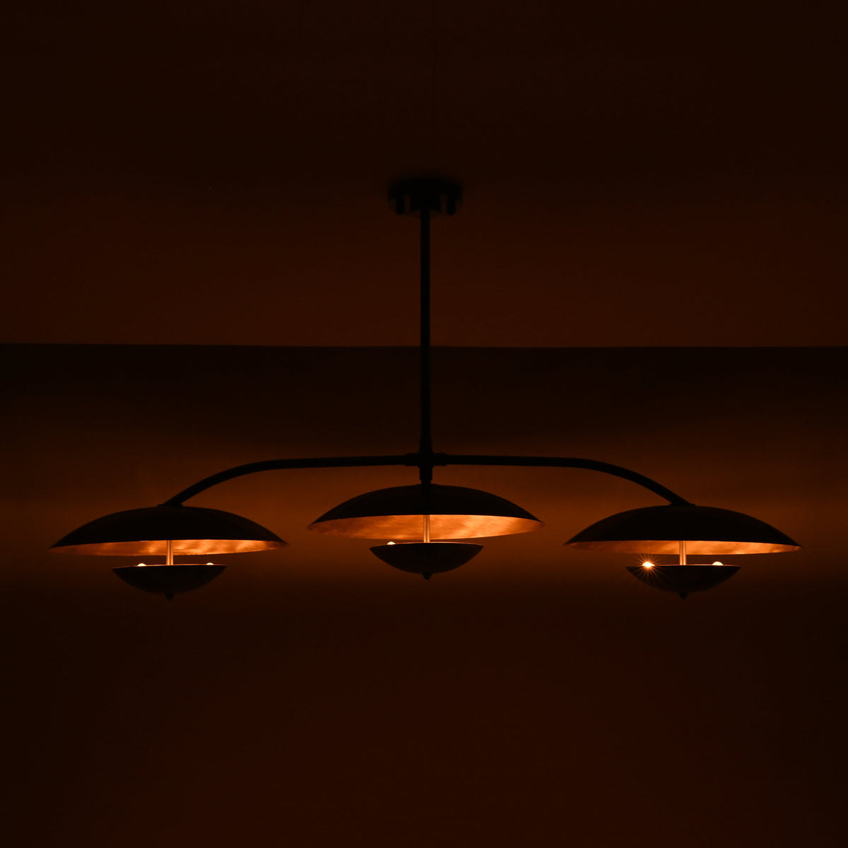 Modern dining room chandelier with three balanced shades, central ceiling rod, and elegant curved arm design