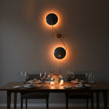 Asymmetrical brass wall sconce design with two circular blue shades and warm decorative wall lighting effect