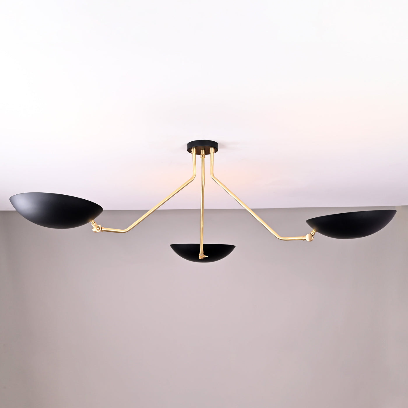 Front view of modern black and brass 3-light bowl chandelier with sculptural arms and matte black shades.