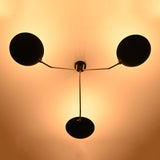 Bottom glowing view of black bowl chandelier illuminating the ceiling with warm ambient light and stylish brass arms.