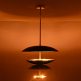 Black and brass disc chandelier showing illuminated lower bowl with soft diffused light