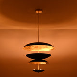 Installed black and brass disc chandelier creating warm ambient indirect lighting in a modern interior