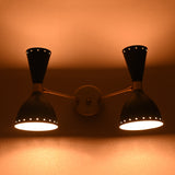 Double cone brass wall sconce with upward and downward warm glow in dark ambiance