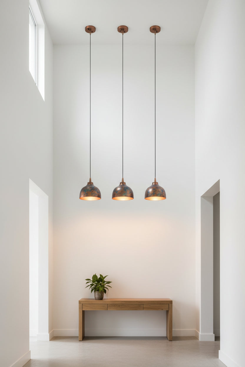 Set of four blue copper dome pendant lights with black hanging cords and copper ceiling canopies above a dining table