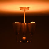 Brass 3-light chandelier emitting soft warm illumination, showcasing elegant cup shades and a minimalist brass stem.