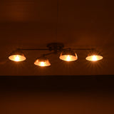 Low-profile handmade brass chandelier with four illuminated dome shades, casting golden lighting on the ceiling.
