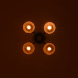 Four light brass bowl ceiling fixture casting warm ambient glow in a dark interior setting.