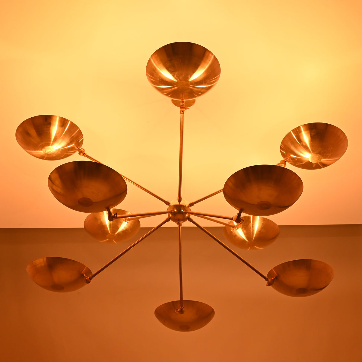 Warm-lit view of the 10-light brass bowl chandelier casting soft ambient ceiling illumination.