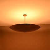 Warm night view of brass bowl pendant light casting soft ambient uplighting onto the ceiling.