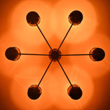 Ceiling light pattern created by perforated brass cone shades casting warm decorative glow in a handcrafted chandelier.