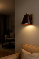 Brass cone wall light installed on wall providing warm ambient lighting in living room