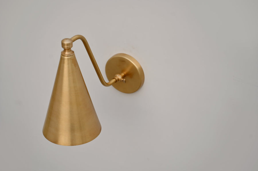 Handmade fixed-arm brass cone wall light with brushed satin finish, designed for modern and minimalist interiors