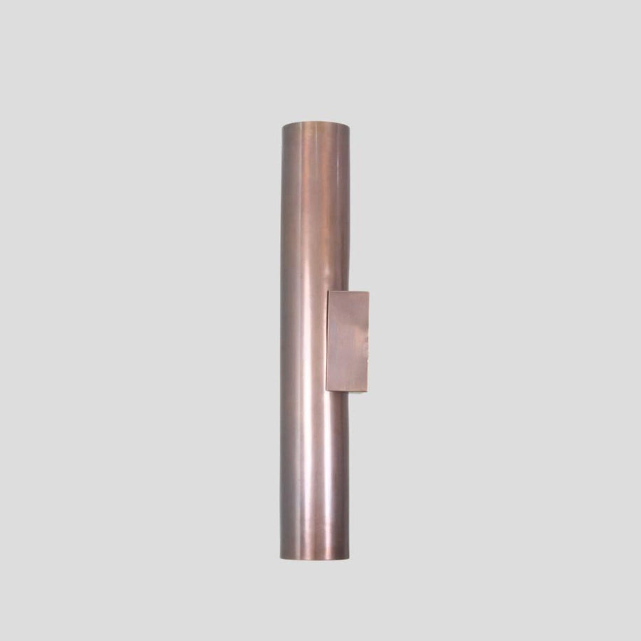Handmade brass cylinder wall sconce light with warm glow, minimalist industrial design, crafted by Brass Leaf Studio.