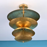 Low angle view of handcrafted brass disc ceiling light highlighting layered bowls and soft indirect illumination.