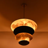 Close-up of layered brass disc chandelier with dramatic warm lighting and handcrafted metal finish
