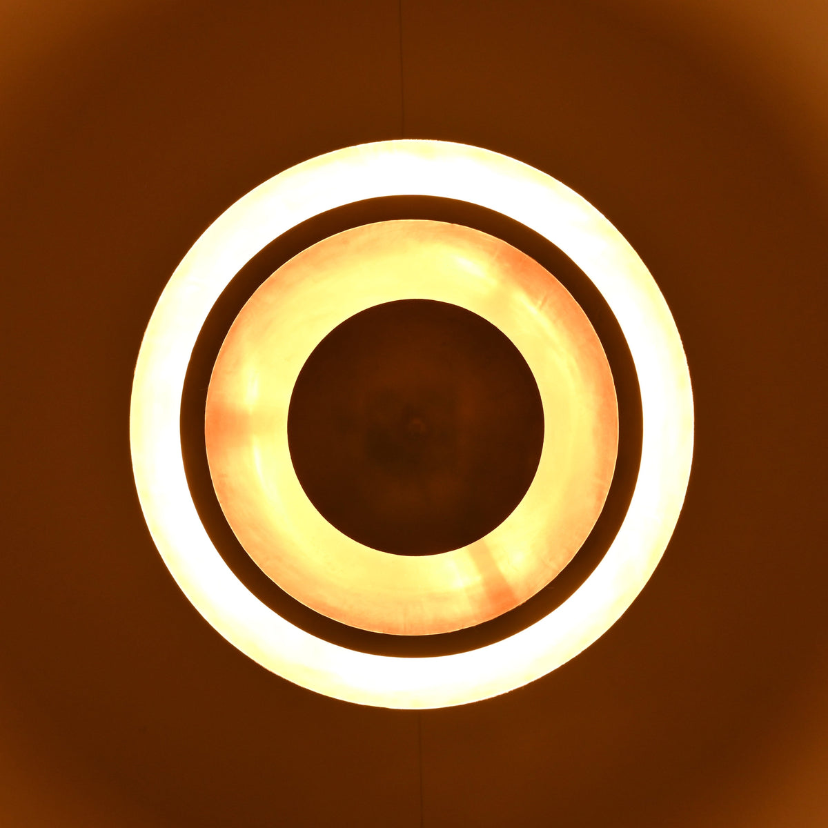 Artistic view of brass chandelier creating concentric ring lighting effect on ceiling