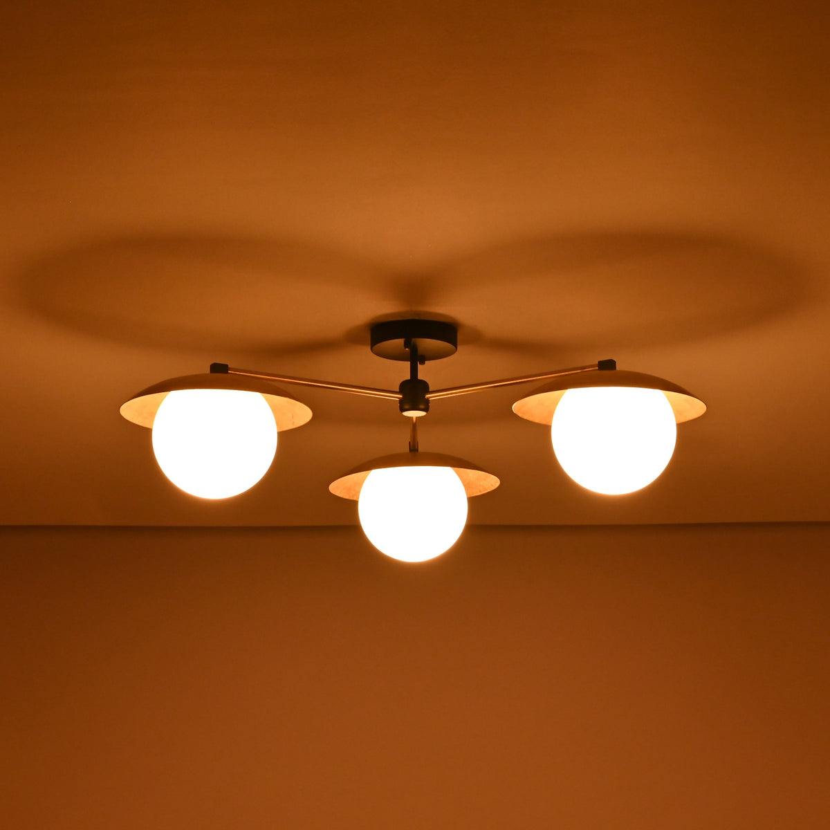3 light brass disc flush mount ceiling light shown in a dark room with warm diffused illumination.