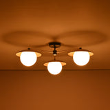 3 light brass disc flush mount ceiling light shown in a dark room with warm diffused illumination.