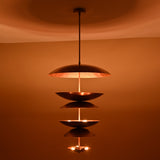 Nighttime ambiance shot of 9-light brass disc chandelier highlighting its layered dome design and soft glowing illumination