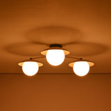 3 light brass disc flush mount ceiling light emitting a soft warm glow in a low light setting.