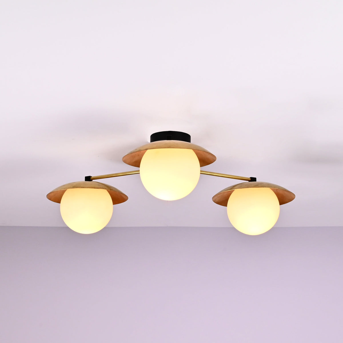 Close view of brass disc shades and opal glass globes on a 3 light flush mount ceiling fixture.