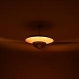 Warm ambient lighting from brass disc chandelier showing indirect uplight effect in a dim interior