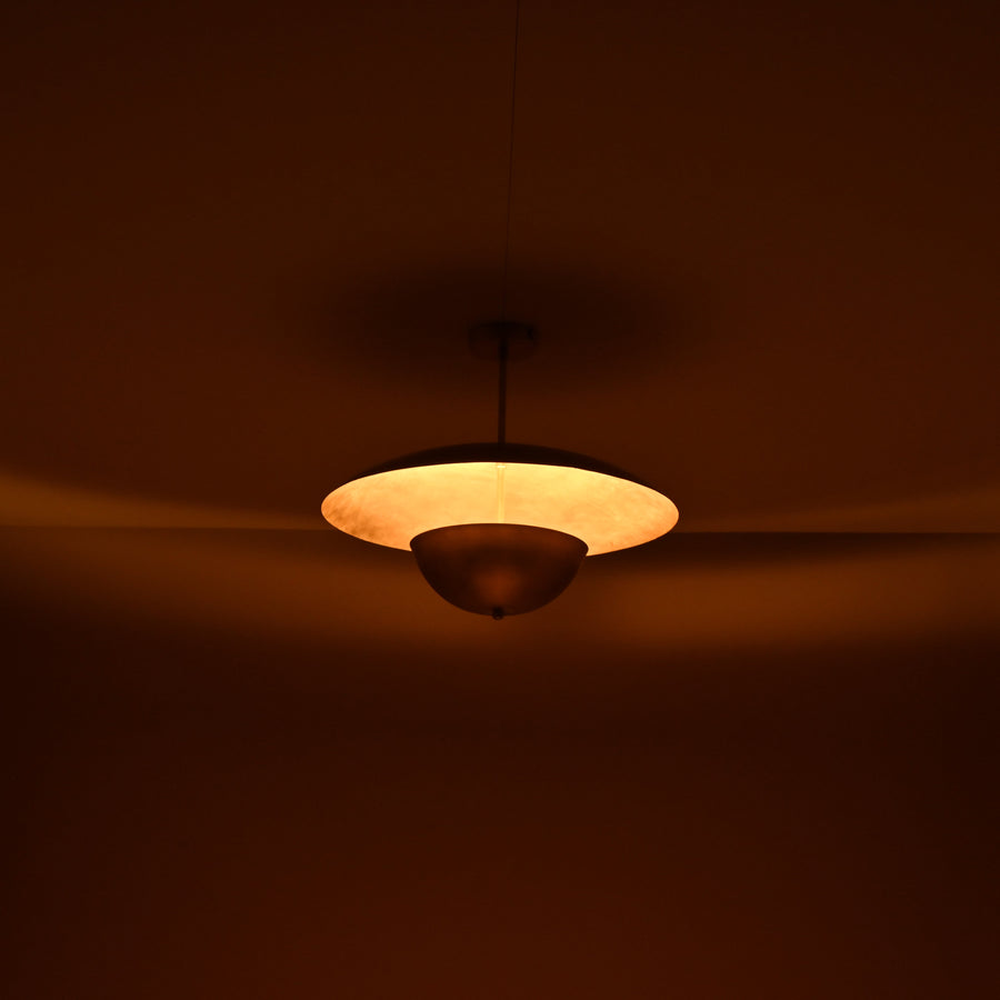 Handmade brass disc pendant light with dual dome design in brushed brass finish, shown against beige background