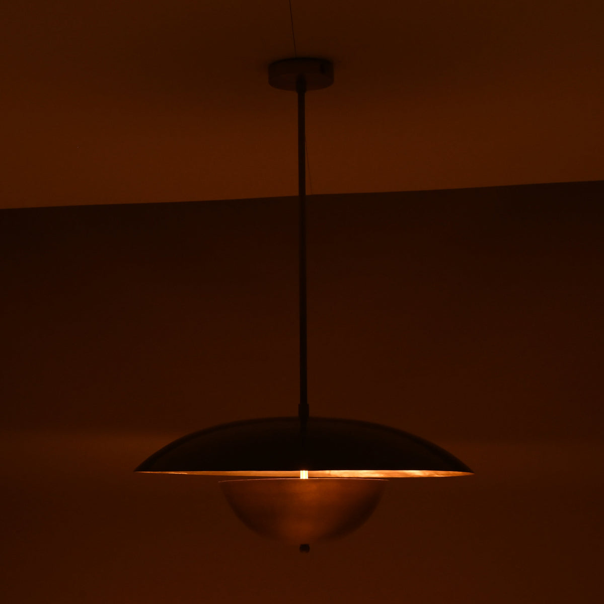 Evening ambiance shot of brass dome pendant with soft downward glow and golden ceiling illumination