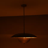 Evening ambiance shot of brass dome pendant with soft downward glow and golden ceiling illumination