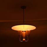Evening view of brass dome pendant chandelier emitting warm indirect glow, mid-century brass ceiling fixture.