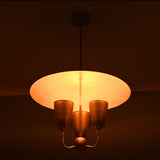 Brass dome shade chandelier with golden warm illumination highlighting the sculpted cups and minimalist brass frame.