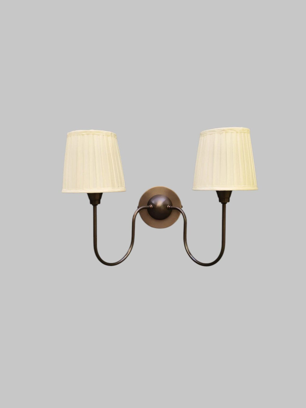 Double arm wall sconce in blackened brass finish with pleated shades – front view