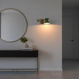Closeup of brass enamel shade wall light showing green hourglass shade, brass band, and arm detail