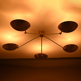 Warm ambient lighting effect from brass flushmount chandelier with bowl shades illuminating the ceiling.