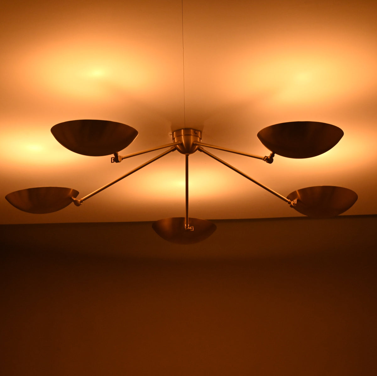 Warm ambient lighting effect from brass flushmount chandelier with bowl shades illuminating the ceiling.
